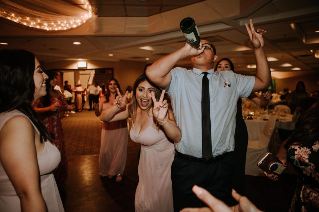 Wedding guests out on the dancefloor ham it up for the camera while a guy takes a drink directly from a wine bottle. Images courtesy of Premier Pour. 