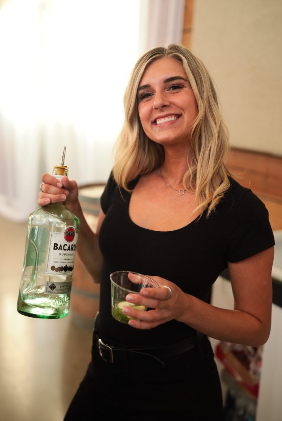 Our bartender Bree holding a bottle of Bacardi Superior rum getting ready to pour a cocktail at The Stables