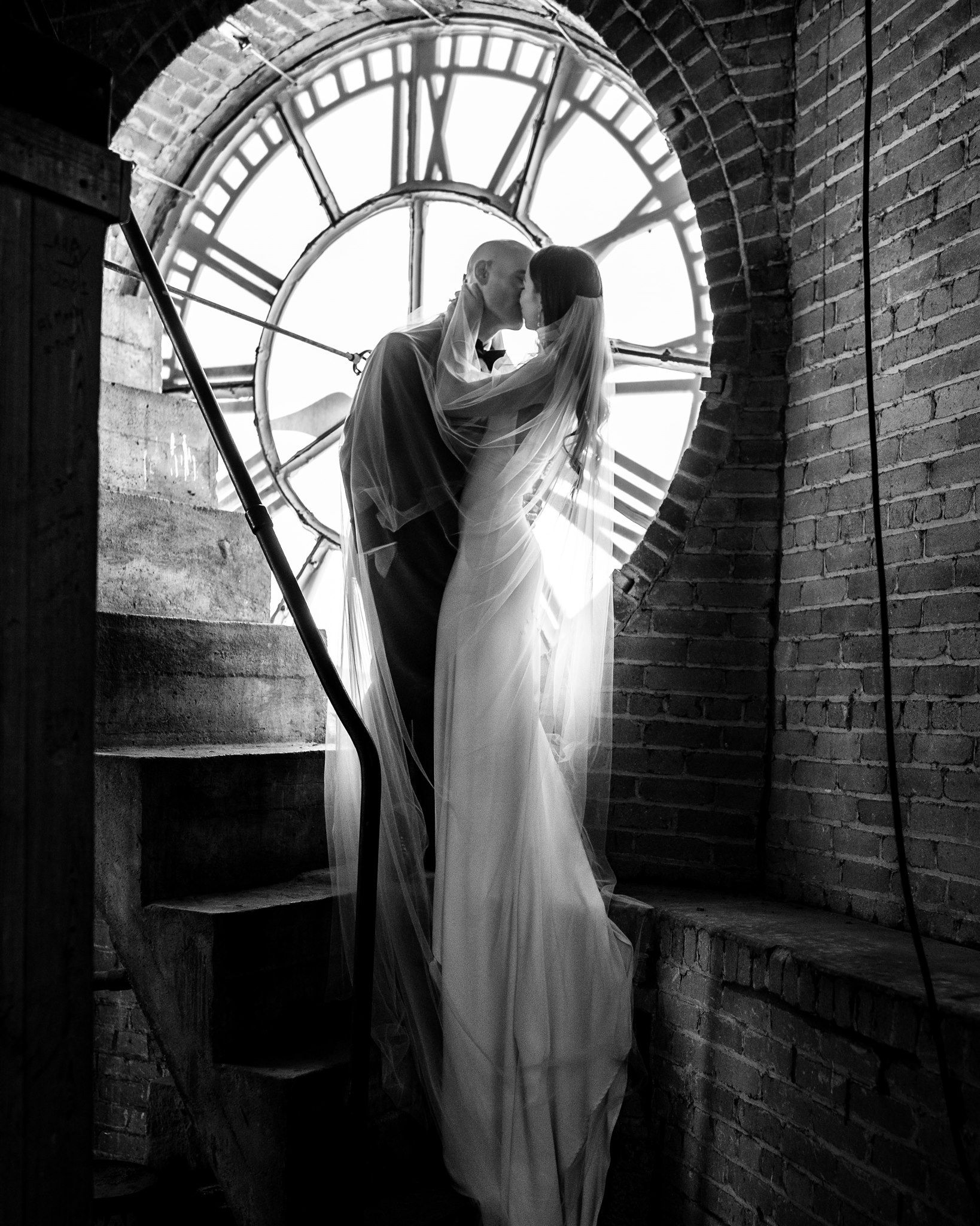 Bride and groom kissing in front of the clock inside the tower at The Collins at the Clocktower in Chelsea, MI