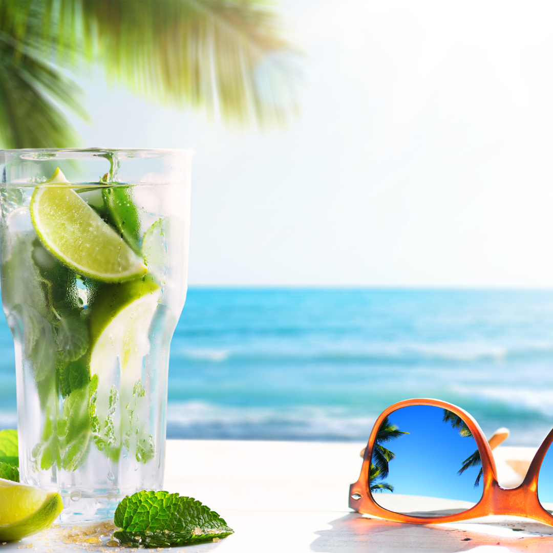 Florida bartending service poured mojito with mint and lime in front of a palm tree on the beach with a pair of sunglasses