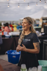 Blonde bartender smiling behind the bar at Barefoot at the Beach