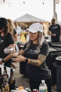 Bartender with arm tattoos and a hat serving a drink at Barefoot at the Beach