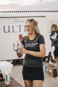 Blonde bartender serving a few canned beverages at Barefoot at the Beach