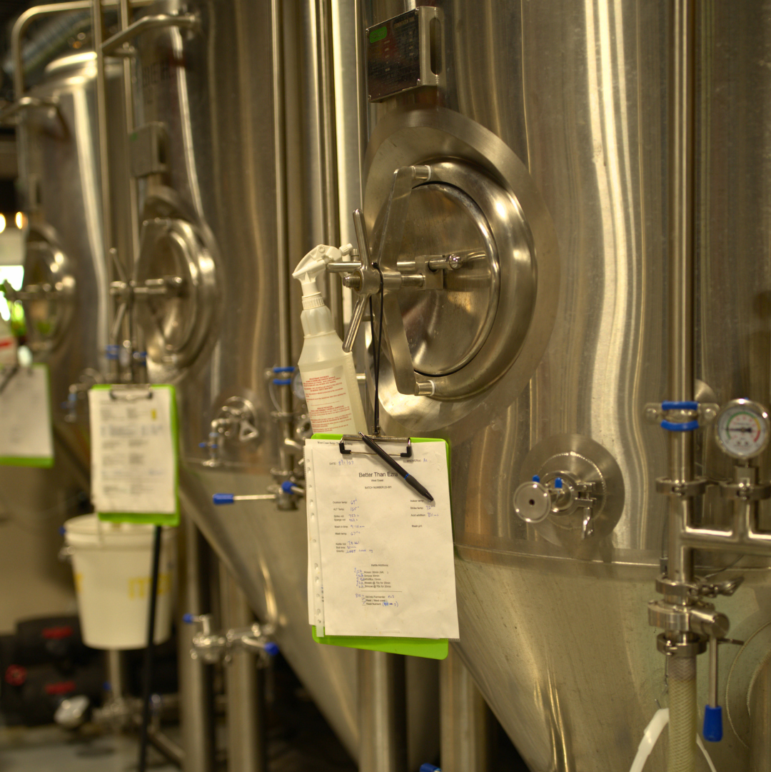 Stainless steel fermentation tanks with recipe clipboards hanging at Oncore Brewing in Swanton, OH