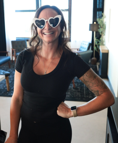 Bartender Alanna F smiling while wearing a pair of heart sunglasses behind the bar at a wedding at The Collins at the Clocktower in Dexter, MI