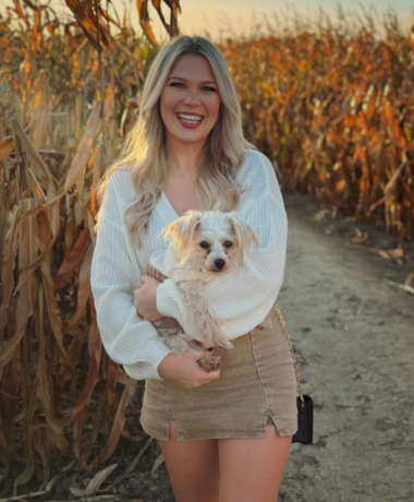 Bartender Ruth G. posing and smiling with her dog in a corn maze.