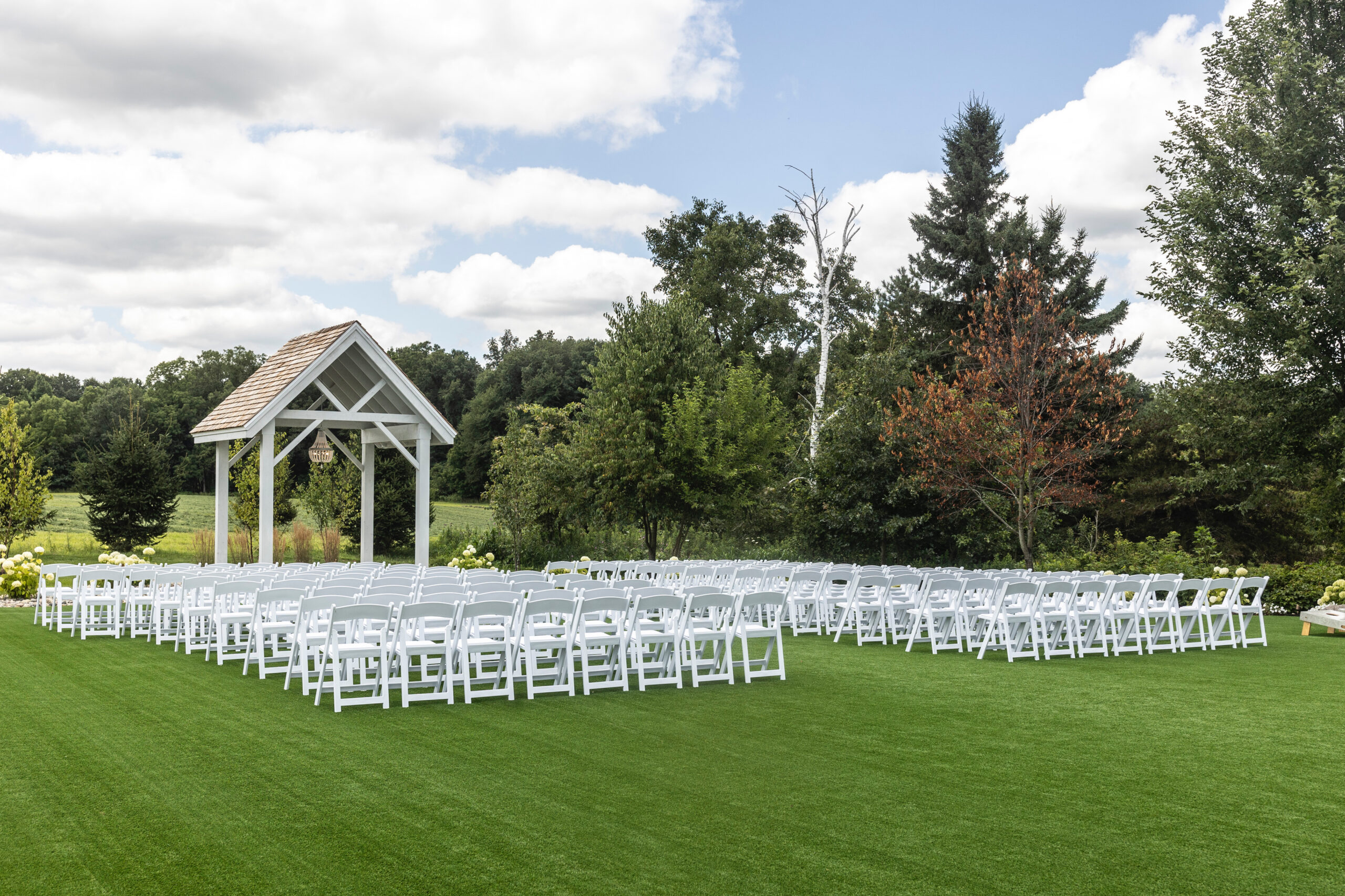 White Birch Wedding Barn in Cement City, MI ceremony space complete with beautiful artificial turf, white resin chairs, and ceremony arch